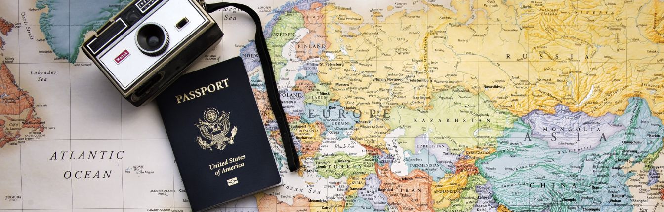 A map of Europe with an American passport and camera on top of it.