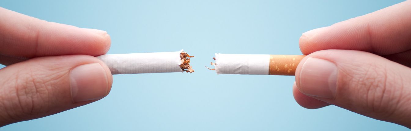 A person holding a cigarette that's been broken in half.