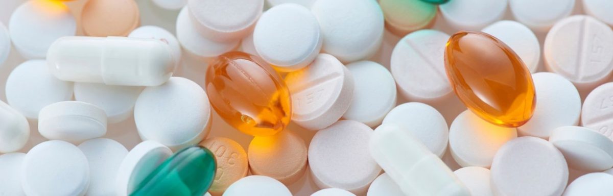 White, orange and teal pills in a pile together.
