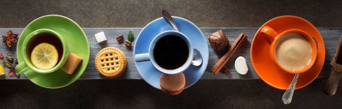 A top-down view of three different coffee drinks in green, blue, and red mugs.