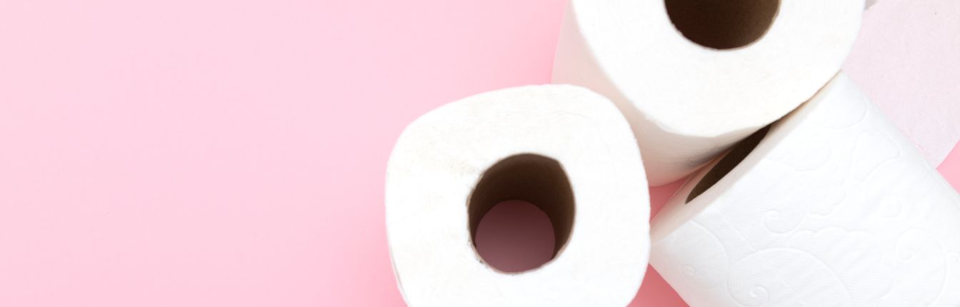 Three rolls of toilet paper on a light pink background.